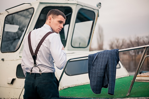 Przystojni młodzi męscy biznesmenów stojaki na doku przy łódkowatą stacją