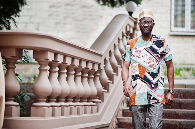 Przystojny afro amerykański mężczyzna noszący tradycyjną czapkę i okulary w nowoczesnym mieście