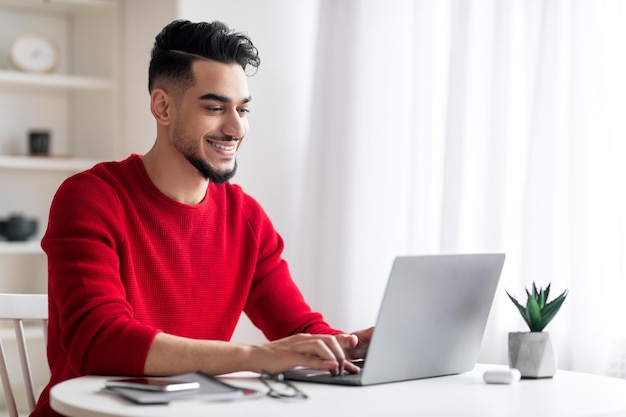 Przystojny arabski mężczyzna freelancer pracujący na laptopie w domowym biurze