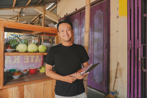 Zdjęcie przystojny azjata uśmiecha się, sprawdzając swój kiosk satay