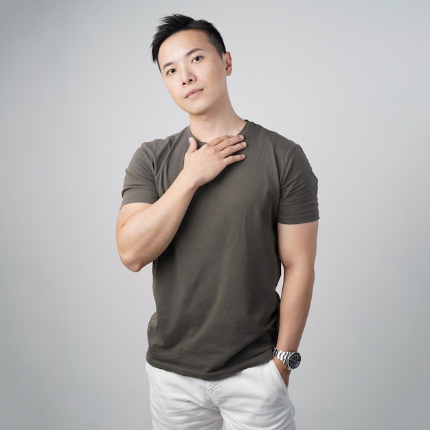Przystojny azjatycki mężczyzna t shirt dotykający szyi izolowanej szarej ściany