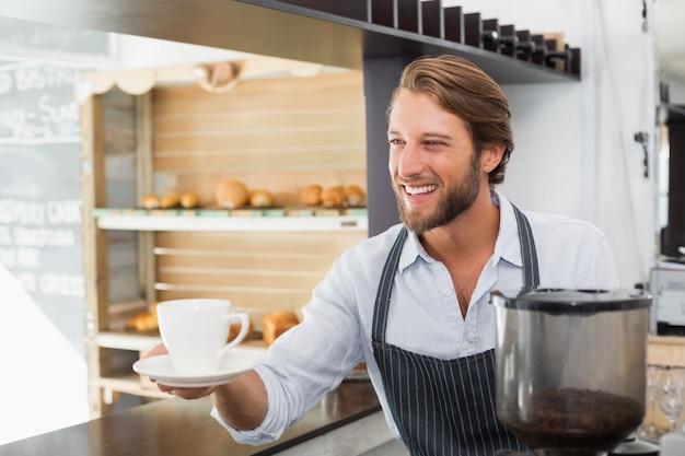 Przystojny barista oferuje filiżankę kawy