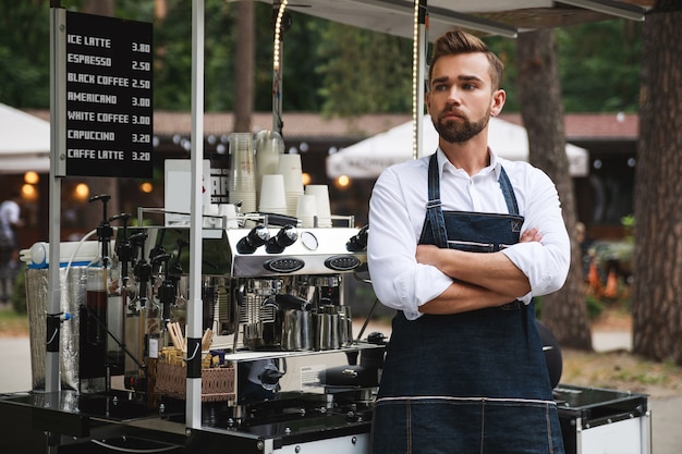 Przystojny barista podczas pracy w swojej ruchomej ulicznej kawiarni