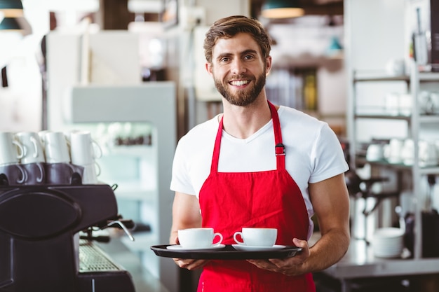 Przystojny barista trzyma dwa filiżanki kawy