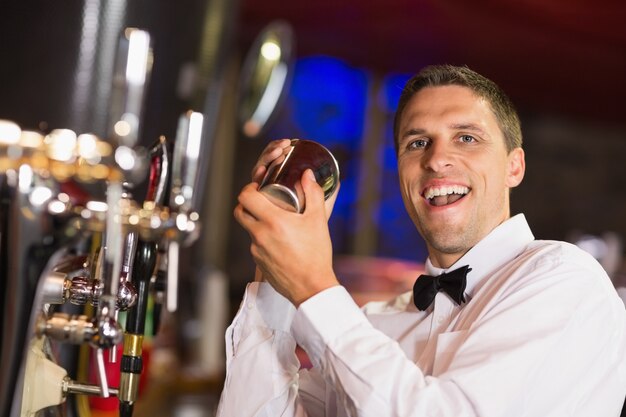 Przystojny barman ono uśmiecha się przy kamerą robi koktajlowi
