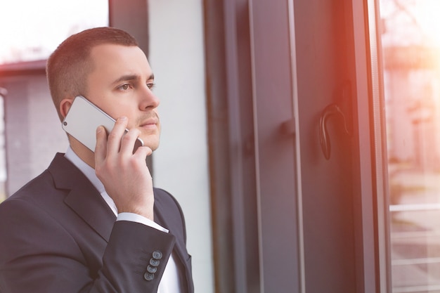 Przystojny biznesmen na sobie czarny garnitur za pomocą telefonu