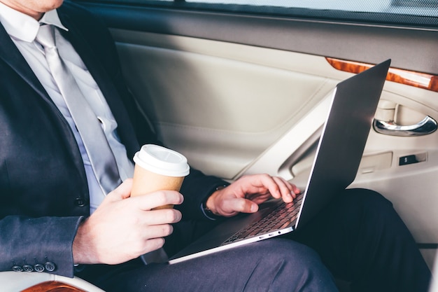 Przystojny biznesmen pracuje na laptopie siedzi na tylnym siedzeniu samochód