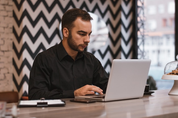 Przystojny Biznesmen Używa Laptop Przy Miasto Kawiarnią.