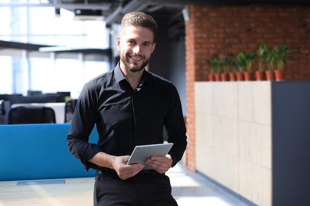 Przystojny biznesmen za pomocą tabletu w biurze.