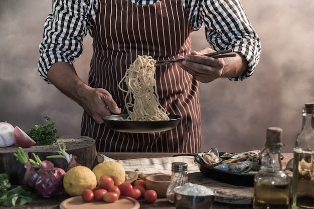 Zdjęcie przystojny brodaty cheef kucharza prepairing spaghetti na kuchni.