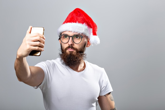 przystojny brodaty mężczyzna w santa hat przy selfie