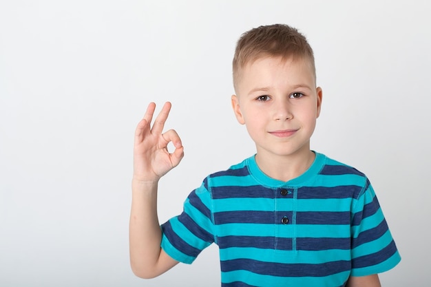 Przystojny chłopak wygląda na zły Dziecko jest obrażone, grozi, pokazuje pięść Wściekłe, urażone, agresywne dziecko Portret na tle białego studia Koncepcja ludzkich emocji dla dzieci