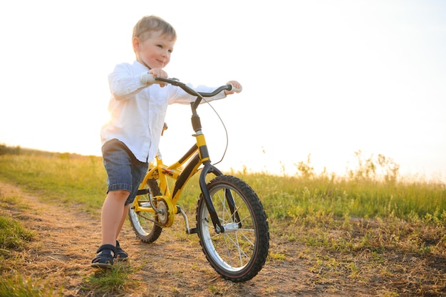 Przystojny chłopak z rowerem w letnim polu