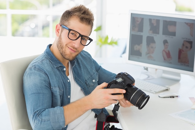 Przystojny fotograf trzyma jego kamerę ono uśmiecha się przy kamerą