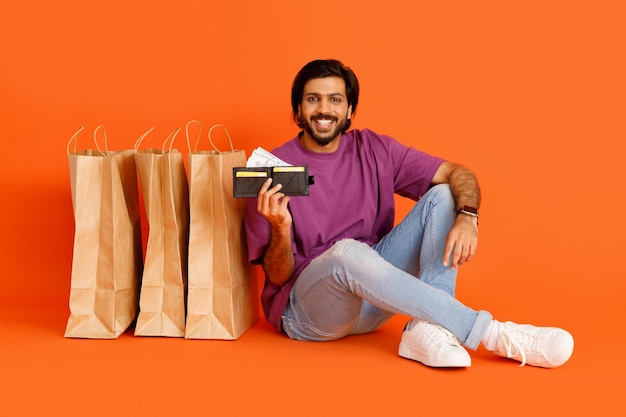 Przystojny hinduski mężczyzna z portfelem i torbami na zakupy