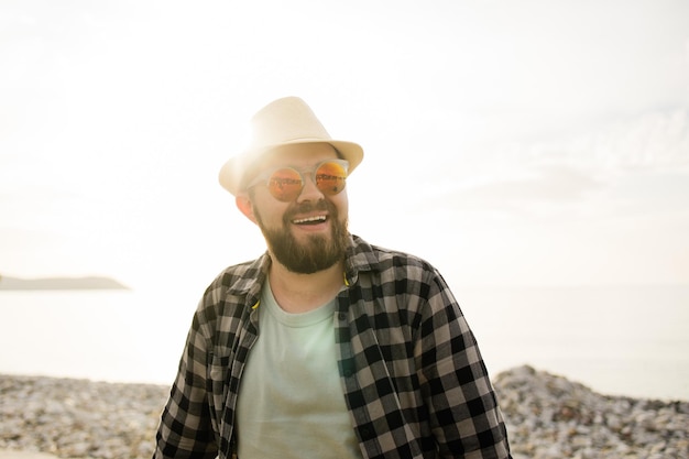 Przystojny i pewny siebie odkryty portret uśmiechniętego mężczyzny w kapeluszu i okularach przeciwsłonecznych na plaży puste miejsce na tekst Wakacje podróże i turystyka letnia