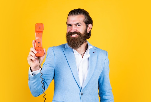 Przystojny kaukaski biznesmen z modną fryzurą w kurtce mówi o epoce cyfrowej telefonu vintage