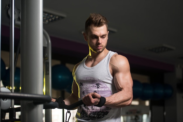 Przystojny Kulturysta Mięśni Fitness W Podkoszulku Wykonuje Ciężkie Ćwiczenia Na Biceps Na Maszynie Z Kablem W Siłowni