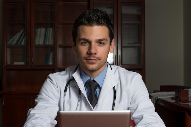 Przystojny lekarz patrzący na monitor komputera w swoim gabinecie