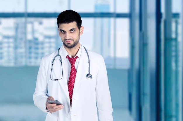 Zdjęcie przystojny lekarz za pomocą telefonu komórkowego w szpitalu