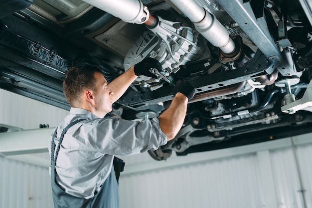 Przystojny mechanik w mundurze pracujący w serwisie samochodowym