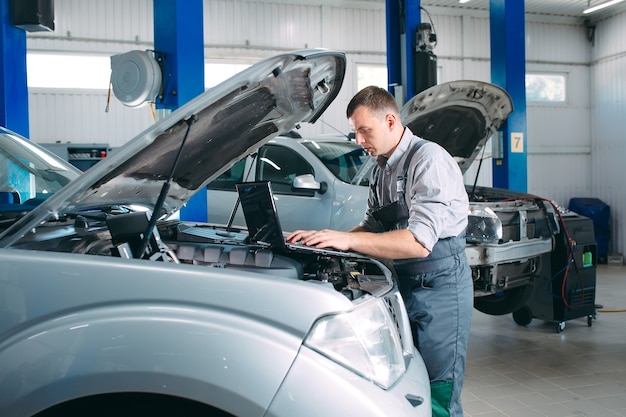 Przystojny mechanik w mundurze pracujący w serwisie samochodowym