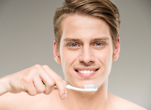 Przystojny mężczyzna czyści zęby z toothbrush w łazience.