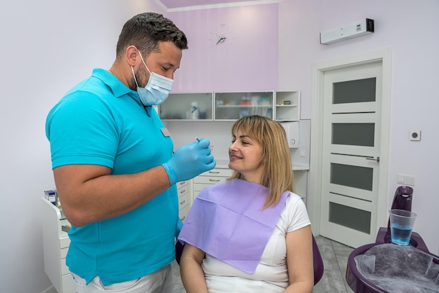 Przystojny mężczyzna dentysta w masce bada zęby pacjenta