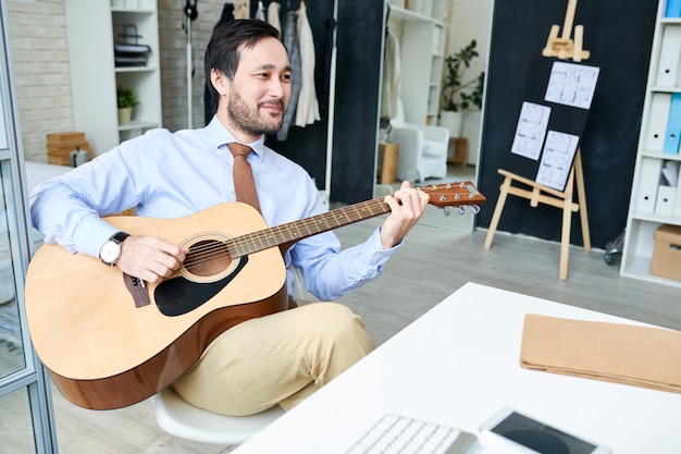 Przystojny Mężczyzna Enjoyin Gitara W Biurze