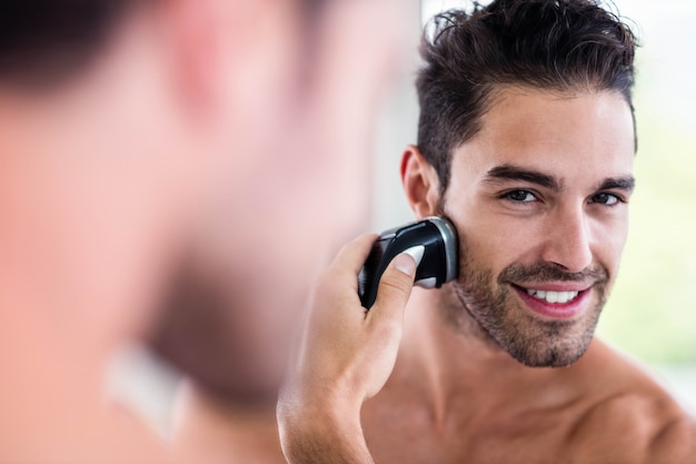 Przystojny mężczyzna golenia w lustrze w łazience