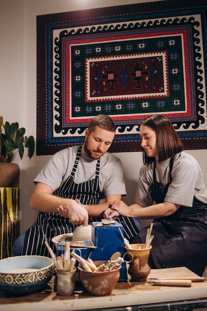 Przystojny mężczyzna i szczęśliwa kobieta zakochana para pracuje na kole garncarskim, podczas gdy mąż i żona w warsztacie garncarskim w kraft creative studiomłody rodzinny sklep biznesowy rzeźbi garnek z gliny