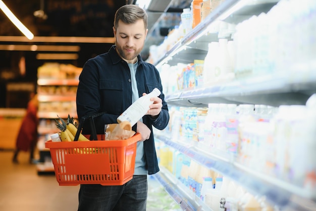 Przystojny mężczyzna kupujący zdrową żywność i napoje w nowoczesnym supermarkecie lub sklepie spożywczym Koncepcja stylu życia i konsumpcjonizmu