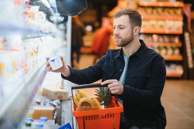 Przystojny mężczyzna kupujący zdrową żywność i napoje w nowoczesnym supermarkecie lub sklepie spożywczym Koncepcja stylu życia i konsumpcjonizmu