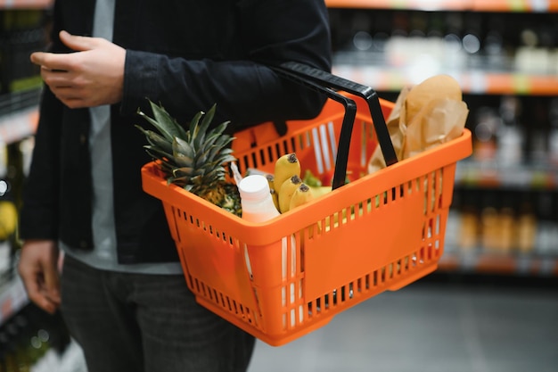 Zdjęcie przystojny mężczyzna kupujący zdrową żywność i napoje w nowoczesnym supermarkecie lub sklepie spożywczym koncepcja stylu życia i konsumpcjonizmu