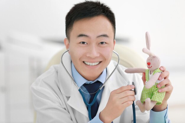 Zdjęcie przystojny mężczyzna lekarz trzymający stetoskop i zabawkę królika