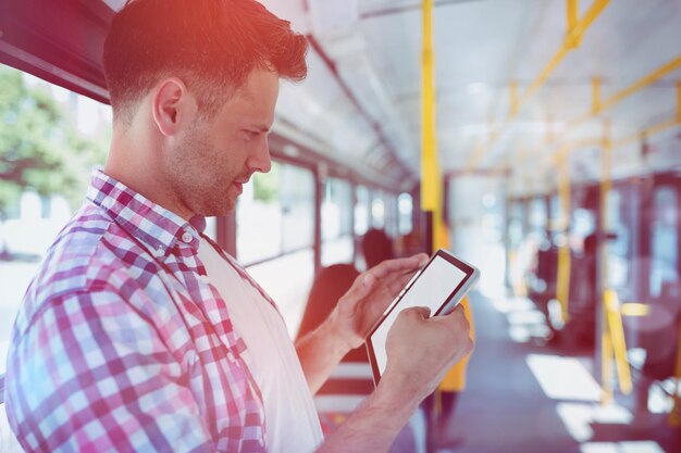 Przystojny mężczyzna patrzący na cyfrowy tablet w autobusie