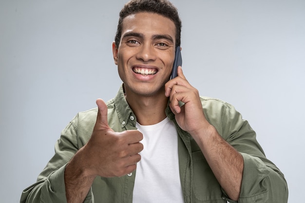 Przystojny mężczyzna pokazujący kciuk w górę mówiący przez smartfona