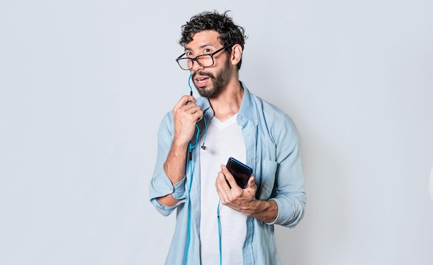 Przystojny mężczyzna rozmawia z zestawem słuchawkowym trzymając telefon młody mężczyzna w okularach ze słuchawkami na białym tle