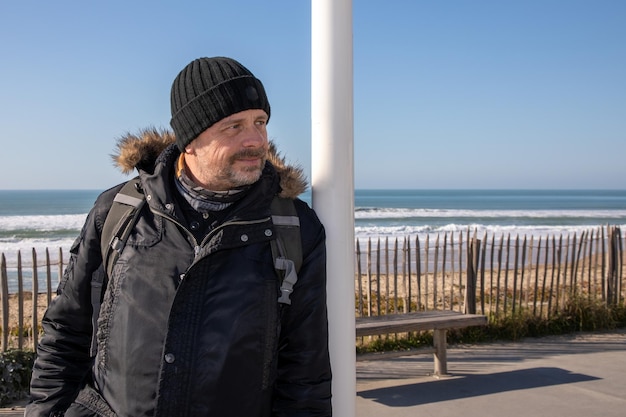 Przystojny mężczyzna szczęśliwy uśmiech w zimie na plaży wybrzeża piasku oceanu