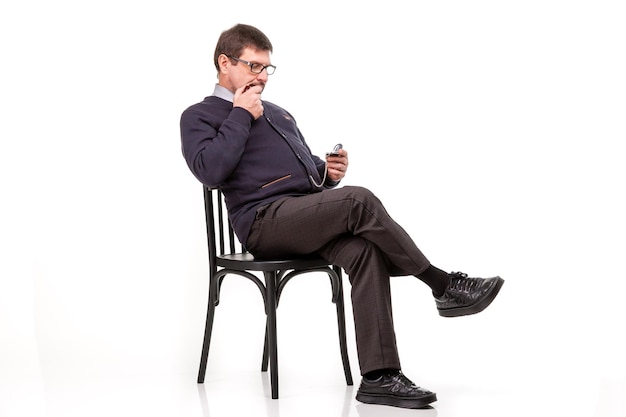 Przystojny mężczyzna w garniturze i okularach siedzi z fajką do palenia Białe tło