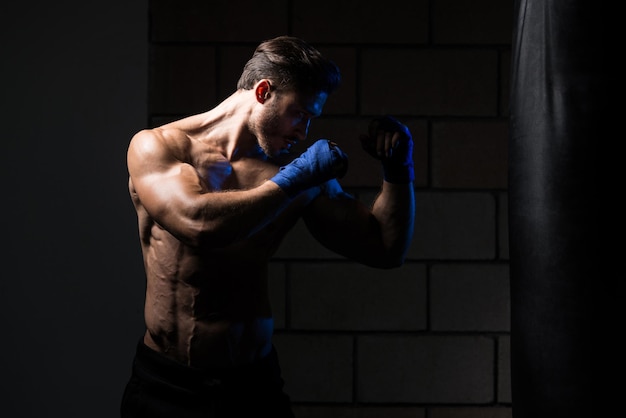 Przystojny mężczyzna w niebieskich rękawicach bokserskich Boks na siłowni Koncepcja zdrowego stylu życia Pomysł na film o boksie