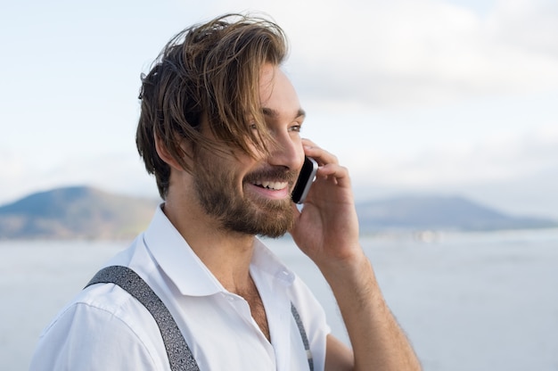 Przystojny mężczyzna w rozmowie telefonicznej na plaży