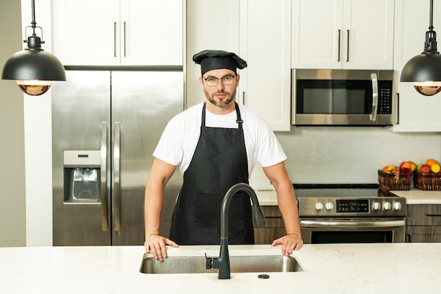 Przystojny mężczyzna w średnim wieku w mundurze szefa kuchni w koncepcji gotowania w kuchni i kulinarnej restauracji