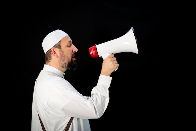 Przystojny mężczyzna z brodą krzyczy przez megafon na hadżdż w mekkah