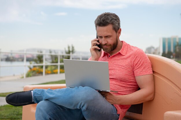 Przystojny Młody Biznesmen Pracujący Z Laptopem Na Zewnątrz Rozmawia Przez Telefon Komórkowy