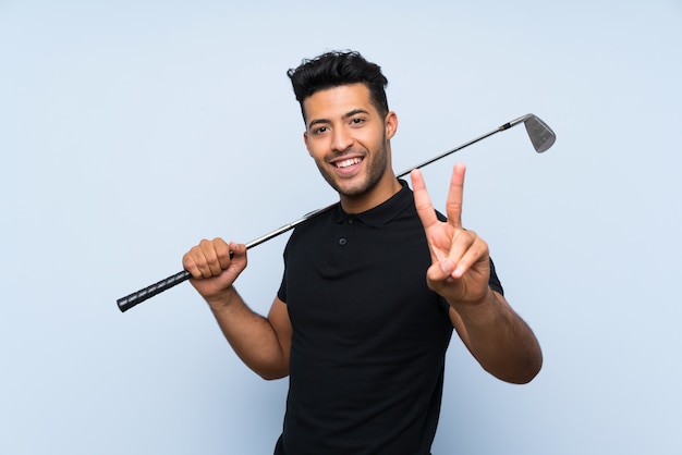 Przystojny młody człowiek bawić się golfa uśmiecha się zwycięstwo znaka i pokazuje