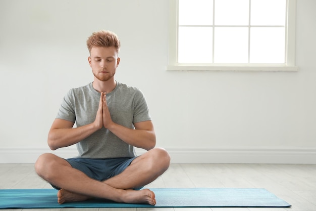 Przystojny młody człowiek praktykujący jogę zen w pomieszczeniu miejsce na tekst