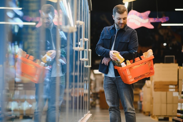 Przystojny młody człowiek wybiera jedzenie w supermarkecie