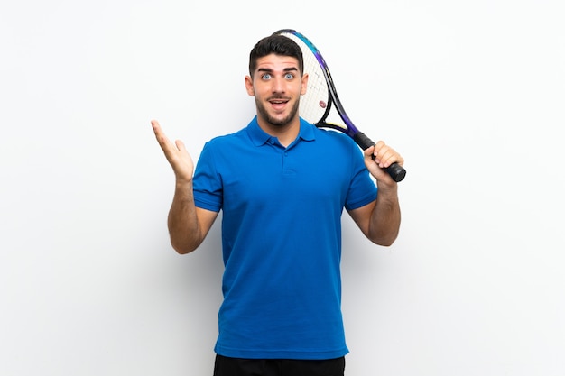 Przystojny młody gracz w tenisa mężczyzna nad odosobnioną biel ścianą z szokującym wyrazem twarzy