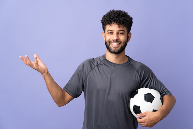 Przystojny młody marokański piłkarz mężczyzna na fioletowym wyciągając ręce na bok, by zaprosić przyjść